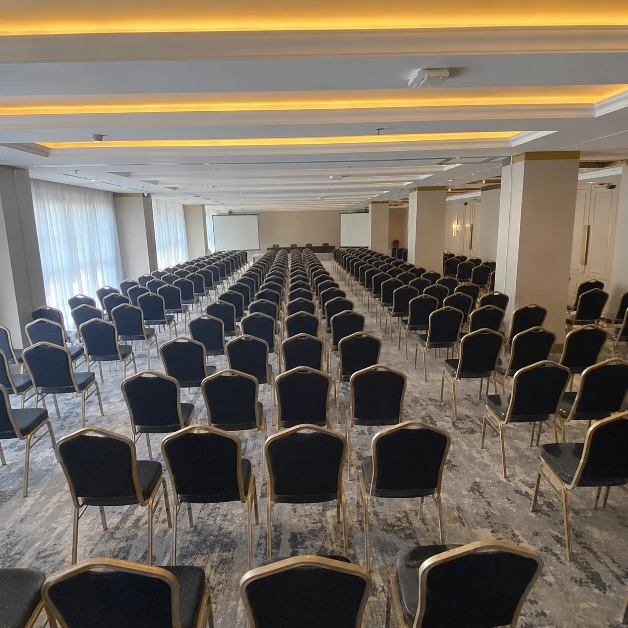 Ruang konferensi dengan penataan gaya teater dan dua layar proyeksi di Maia Hotel Jakarta